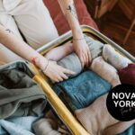 Uma mulher organizando peças de roupa dentro de uma mala de viagem